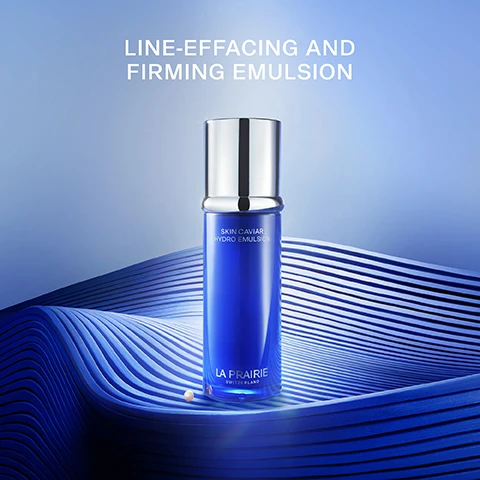 Image 1 - A blue skincare bottle labeled Skin Caviar Hydro Emulsion from La Prairie sits against a wavy blue background with text above that reads LINE-EFFACING AND FIRMING EMULSION.
Image 2 - A glowing yellow orb with sparkling elements around it, featuring the text powered by exclusive cellular complex™ and caviar hydroessence.
Image 3 - A smooth, wavy white texture appears against a gradient blue background, with the text LIGHTWEIGHT SILKY MOISTURISER displayed above it.
Image 4 - Image of a woman with long dark hair holding a blue skincare product bottle up to her face, with the text REDUCES THE APPEARANCE OF LINES AND WRINKLES displayed above.
Image 5 - Image shows three skincare products from La Prairie arranged on a blue background, labeled as follows: 1. PREPARE Essence-in-lotion, 2. LIFT Liquid Lift, and 3. FIRM Hydro Emulsion, with the title YOUR SKIN CAVIAR FIRMRING ROUTINE displayed above.