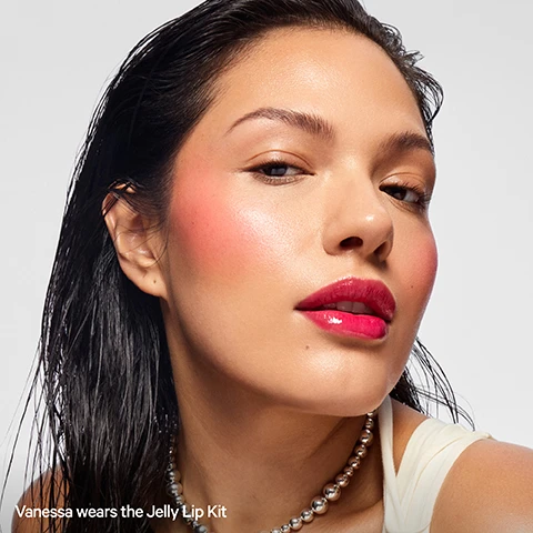 Image 1 - Close-up portrait of a woman with pink blush and shiny pink lipstick Vanessa wears the Jelly Lip Kit. Image 2 - Photo shows pink lip products, a clear bottle of lip oil with an applicator and a pink lip tint stick, with text that says JELLY LIP KIT The ultimate combo for juicy, jelly-glazed lips. LIMITED EDITION KUSH LIP OIL IN STRAWBERRY HAZE light pink with a strawberry banana flavor IN THIS SET ONLY! COOLING WATER JELLY TINT IN BURST poppy pink MILK MAKEUP KUSH LIP OIL / HUILE A LEVRES. Image 3 - A comparison image showing lips with jelly tint in the top section labeled WITH Jelly Tint and the same lips with jelly tint and KUSH lip oil in the bottom section labeled WITH Jelly Tint + KUSH Lip Oil.
