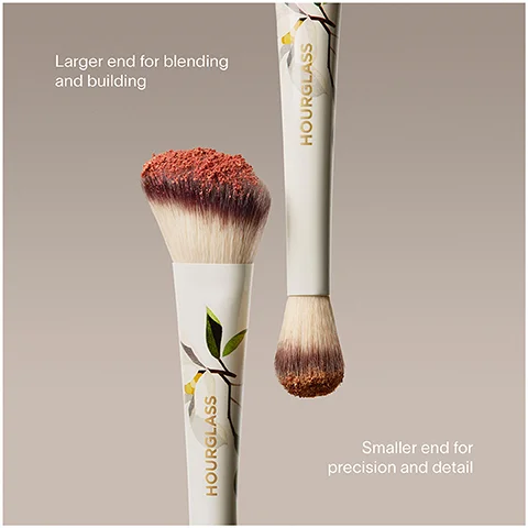 Two Hourglass makeup brushes are shown, one larger angled brush with reddish powder and a label reading Larger end for blending and building, and one smaller rounded brush also with reddish powder and a label reading Smaller end for precision and detail, both brush handles feature a floral design and the word HOURGLASS.