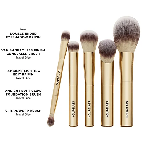 A collection of five Hourglass makeup brushes with gold handles and white and brown bristles is shown alongside their descriptions: New Double Ended Eyeshadow Brush, Vanish Seamless Finish Concealer Brush Travel Size, Ambient Lighting Edit Brush Travel Size, Ambient Soft Glow Foundation Brush Travel Size, and Veil Powder Brush Travel Size, with Hourglass visible on each brush handle.